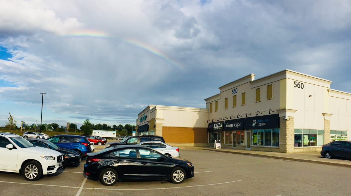 The 560 Copper Creek Drive building with the Copper Creek Dental sign above the storefront, under a rainbow